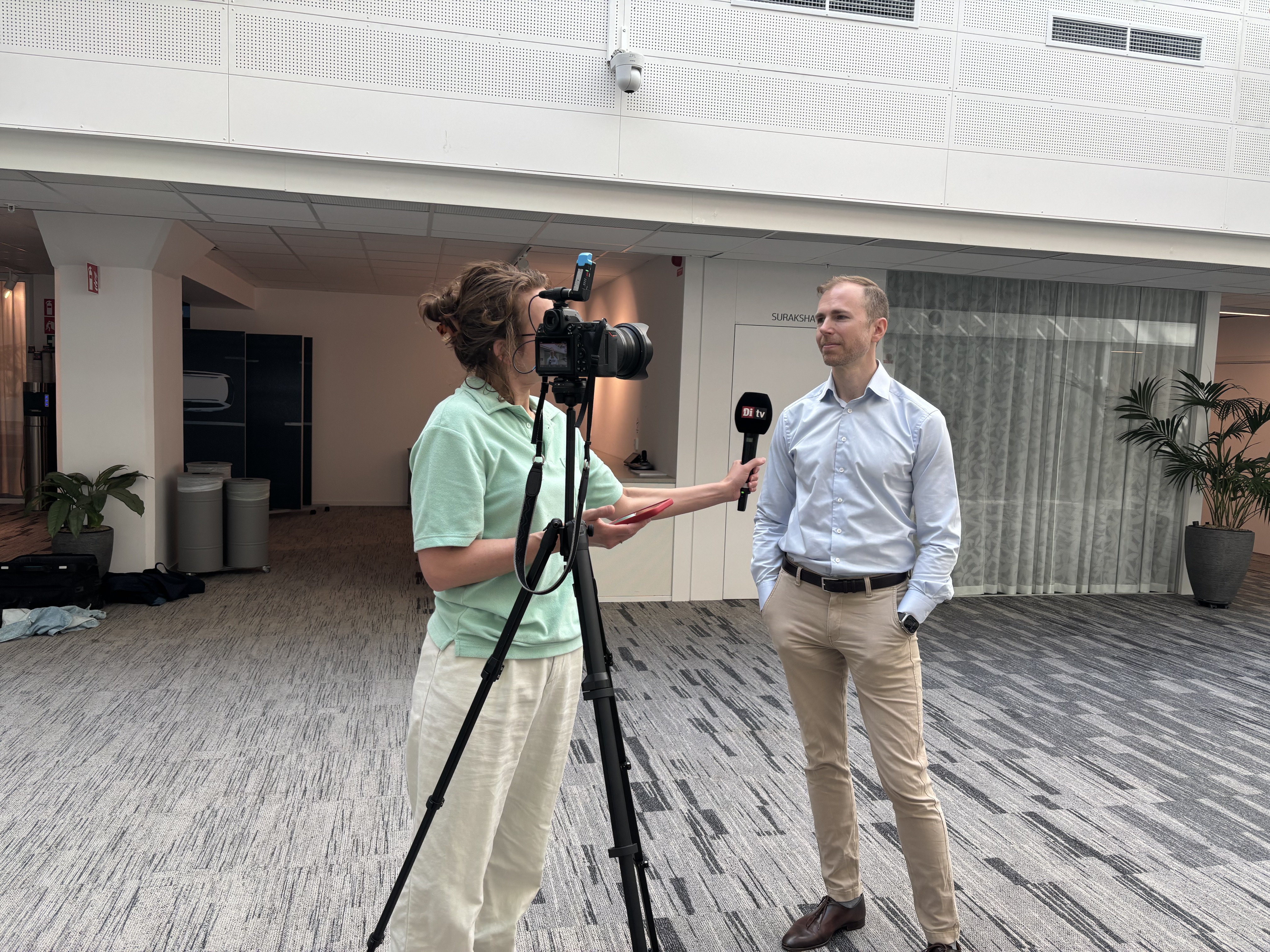 Jonas Lundin standing in front of a camera, being interviewed by a Di reporter holding a camera.